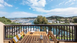 A wooden table with a bowl and a mug on a balcony overlooking a marina with boats and hills in the background. - Appartements de l'Hélios - Îles des Embiez (Six-Fours-les-Plages)