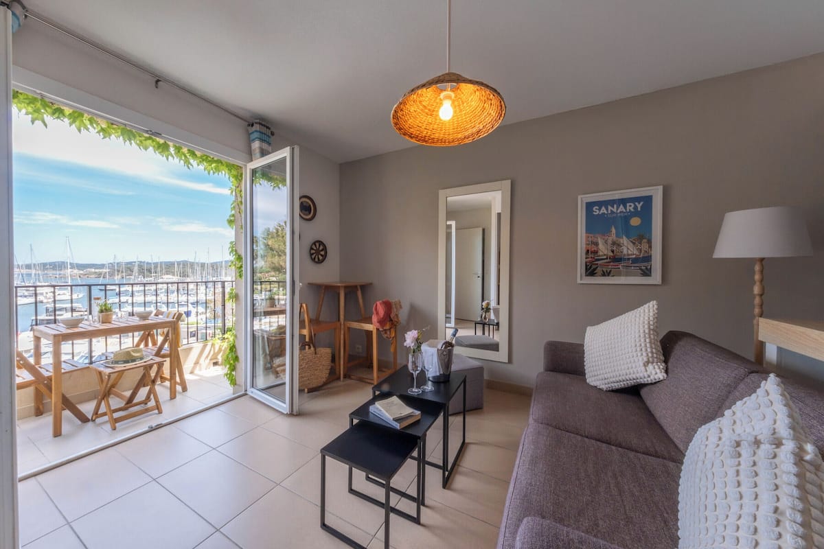Ein modernes Wohnzimmer mit Blick auf einen Hafen, inklusive Sofa, Couchtisch und Pendelleuchte.