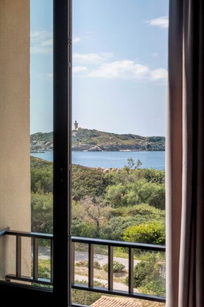 A balcony with a view of a coastal landscape, including a lighthouse and greenery. - Appartements de l'Hélios - Îles des Embiez (Six-Fours-les-Plages)