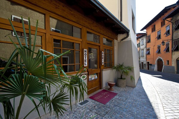 A hotel entrance with a wooden facade, large windows, and a red doormat. - Hotel Doria (Nago-Torbole)