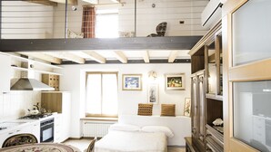 Un dormitorio con cama, cómoda, ventana y una zona de cocina con estufa y alacenas.