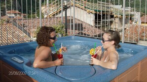 Dos personas en un jacuzzi con montañas al fondo.