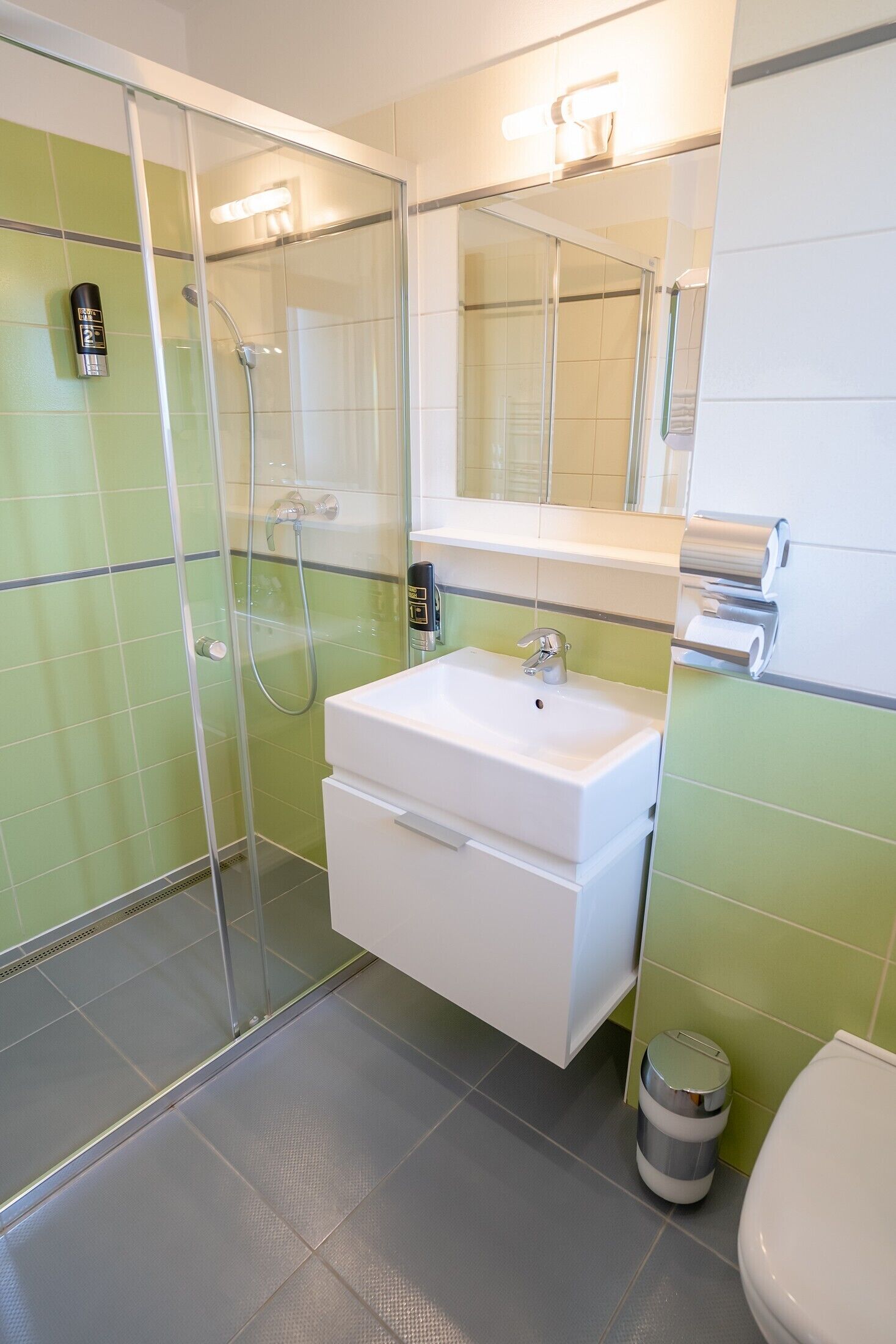 Un baño con cabina de ducha de vidrio, un lavamanos blanco y un inodoro.