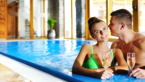 Una pareja en una piscina con iluminación interior clara y ventanas amplias.