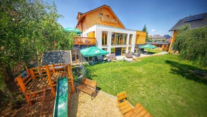 Una casa moderna de dos pisos con una amplia terraza, mobiliario exterior y un césped bien cuidado.