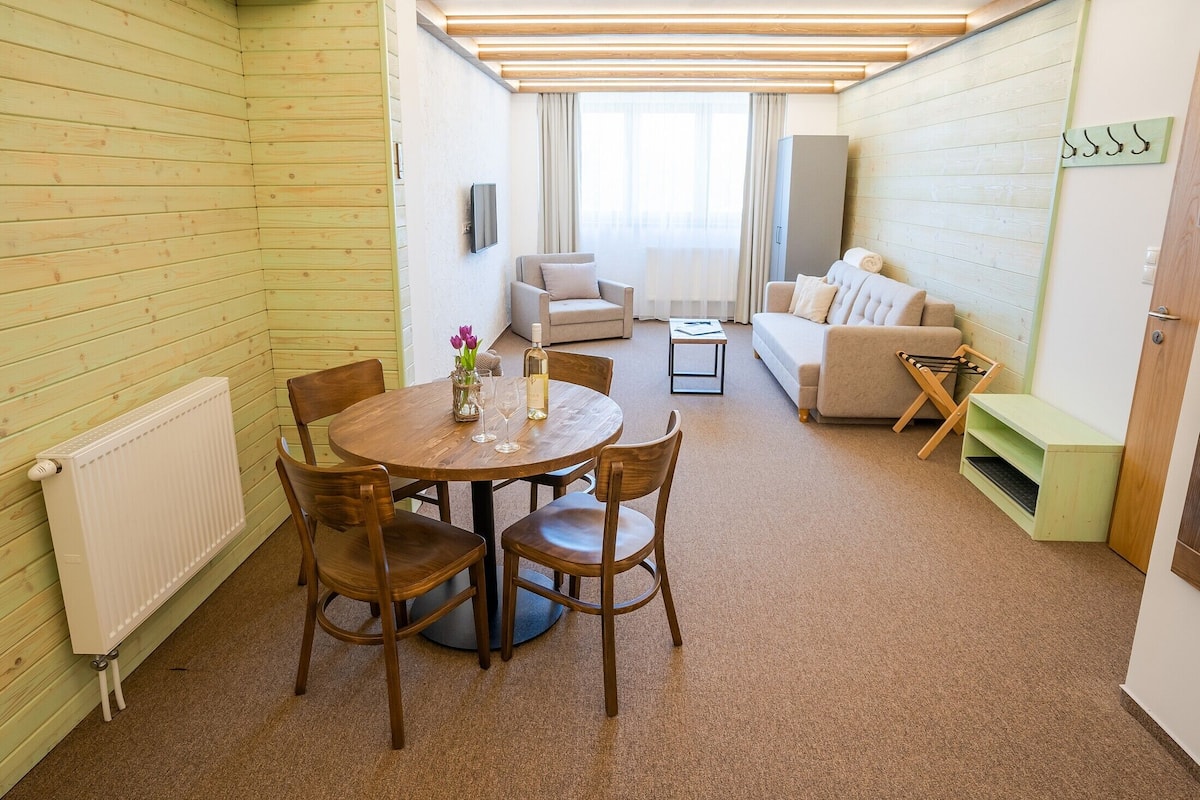 A cozy room with a wooden floor, a round dining table with chairs, a sofa, and a small side table.