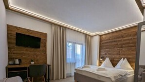 Una habitación de hotel moderna con una pared decorada en madera, una cama grande, un escritorio con una silla y un televisor montado en la pared.