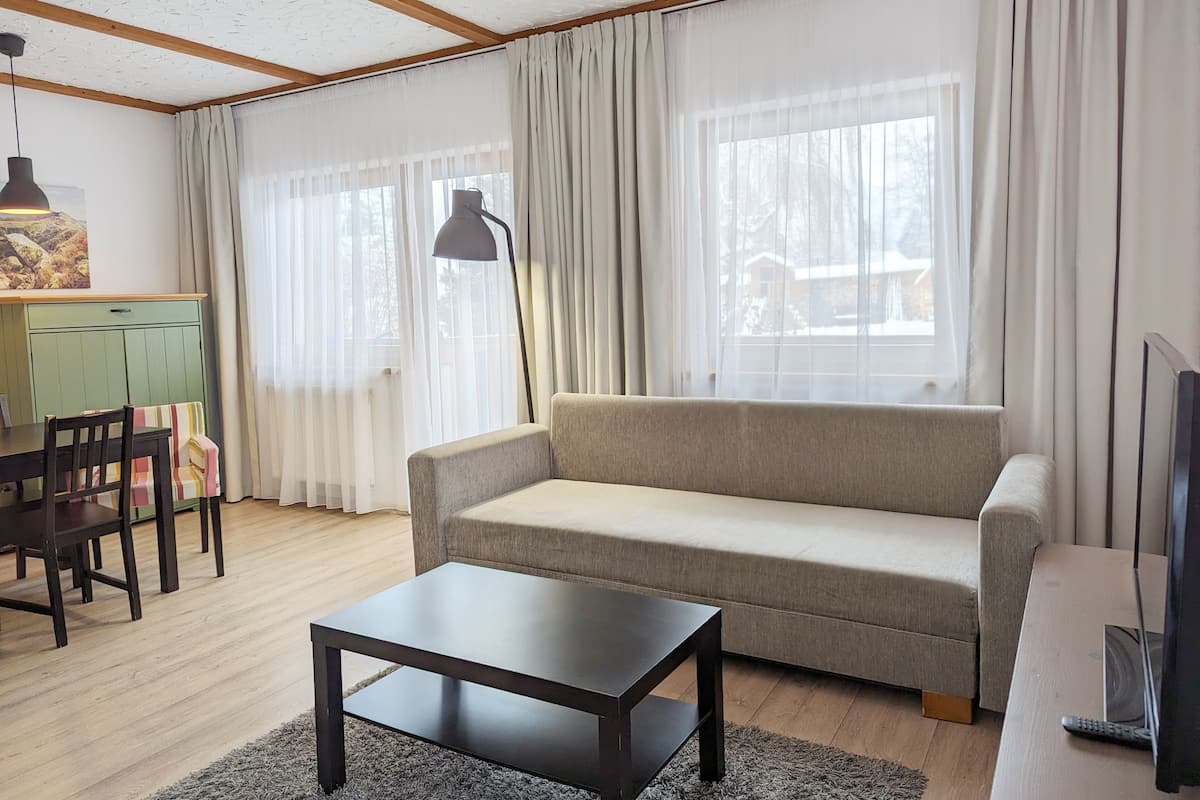 A living room with a sofa, a coffee table, a lamp, and a TV.