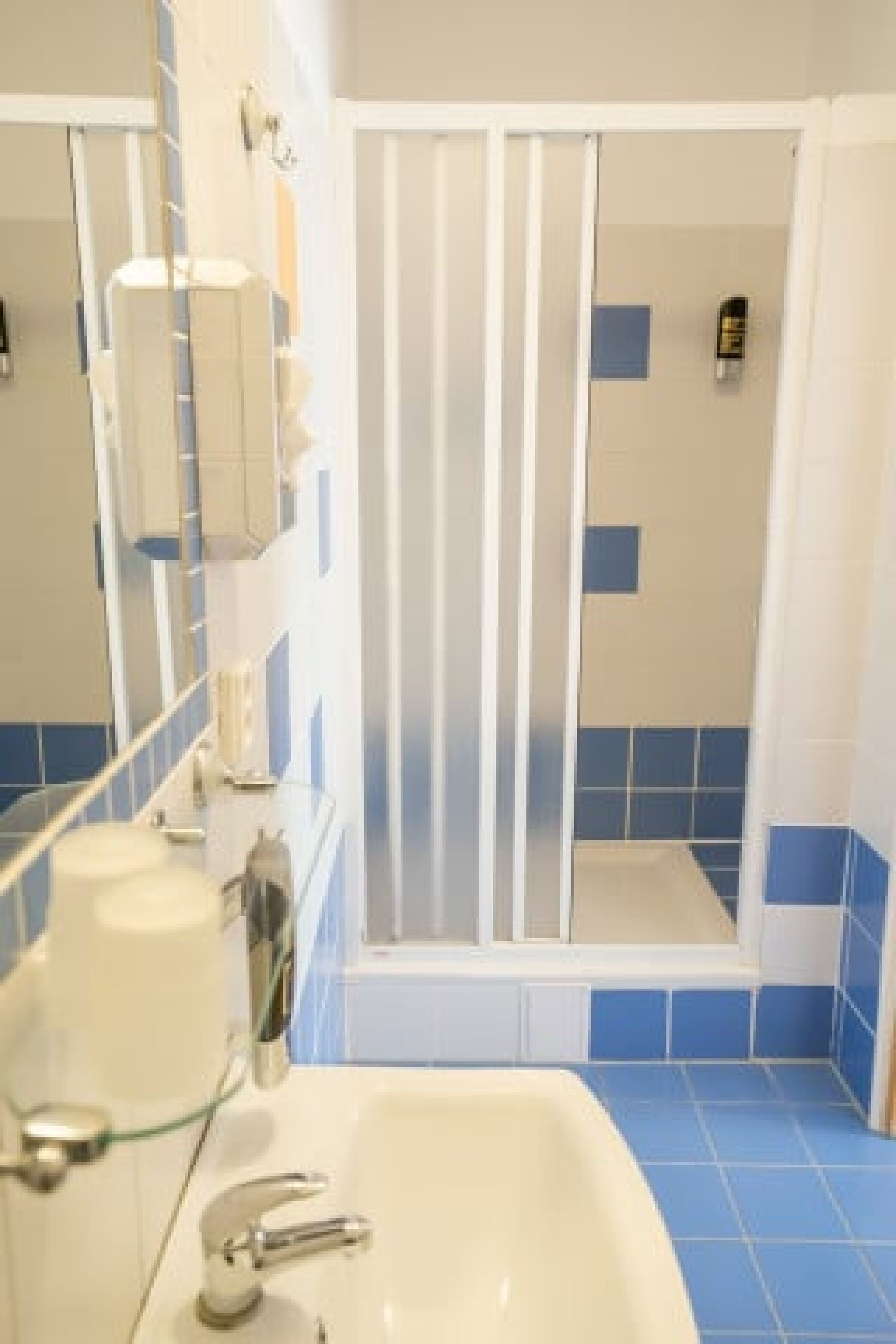 A bathroom with a white sink, a mirror, and a shower enclosure.