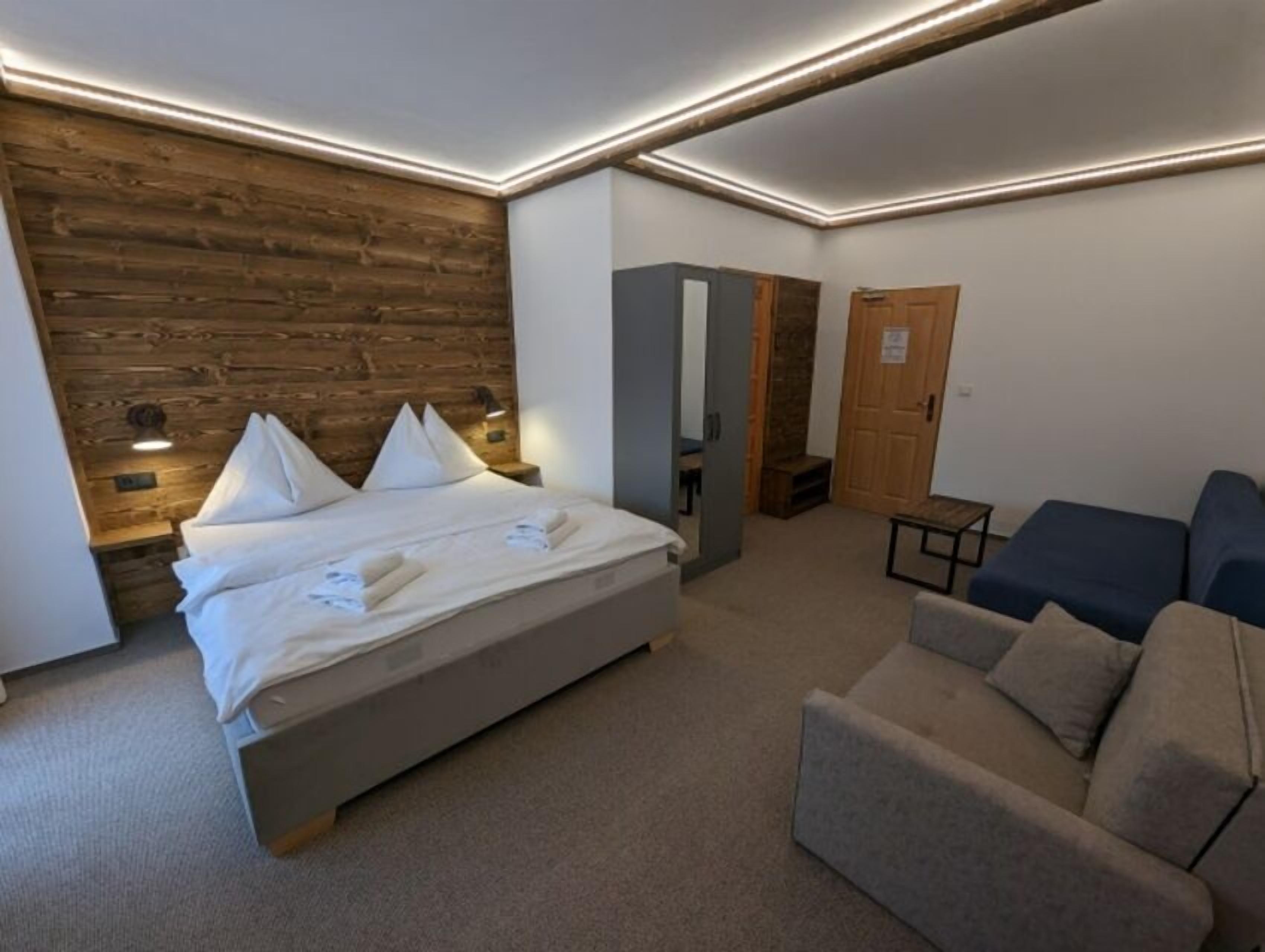 Una habitación de hotel moderna con una pared de acento de madera, una cama con almohadas, un sofá y una pequeña mesa.