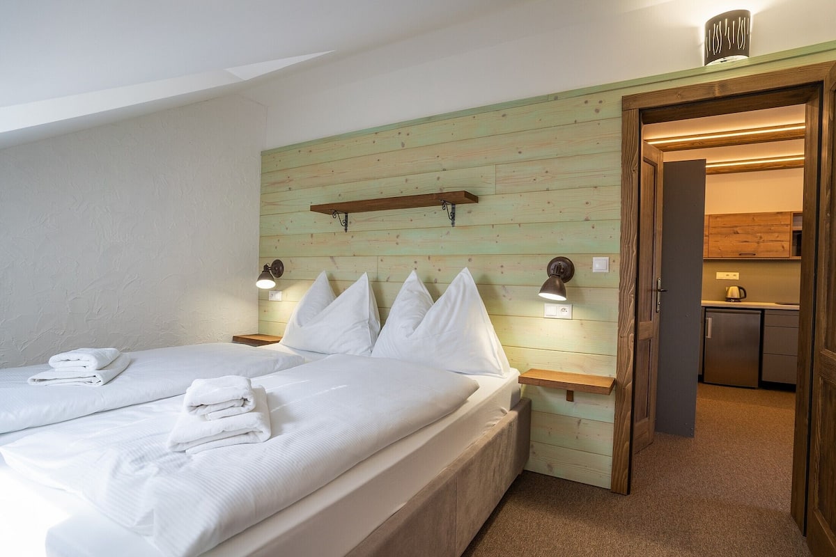 A bedroom with two beds, a wooden headboard, bedside lamps, and a small shelf.