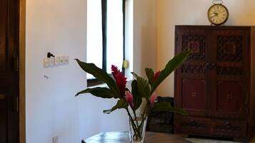 A chandelier with multiple lights, a wooden cabinet, and a vase with flowers in a hallway.
