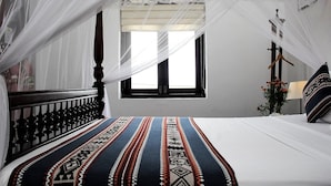 Un dormitorio con cama, ventana y mesita de noche con lámpara.
