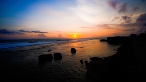 Un atardecer sobre una playa con rocas y un cielo despejado.