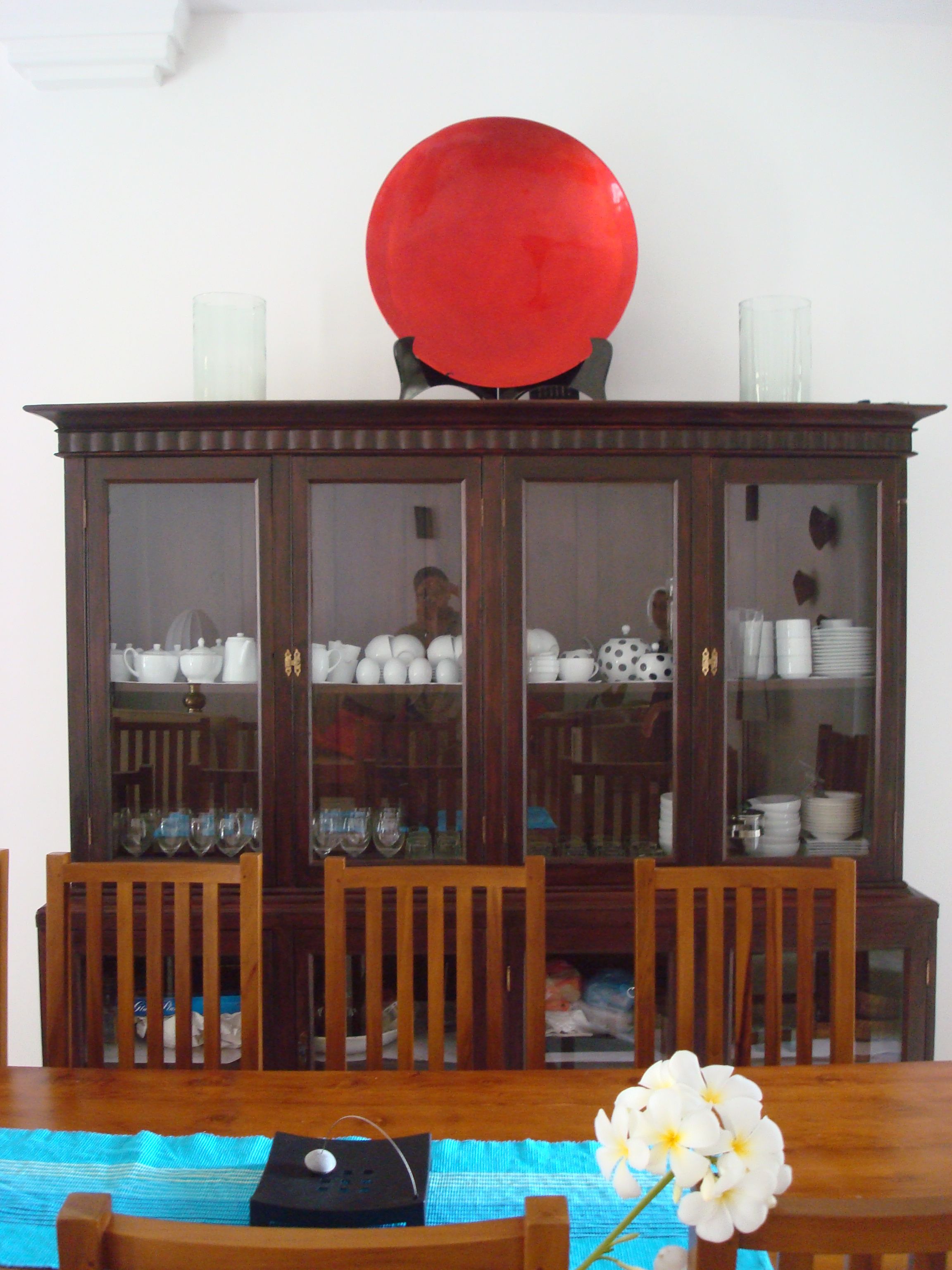 Un comedor con una mesa de madera, sillas y un aparador de vidrio con vajilla.