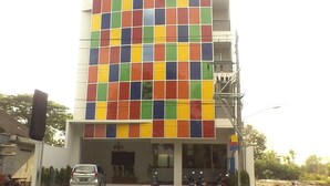 A building with a colorful mosaic facade, a car parked in front, and motorcycles parked outside. - Sarila Hotel Sukoharjo (Sukoharjo)