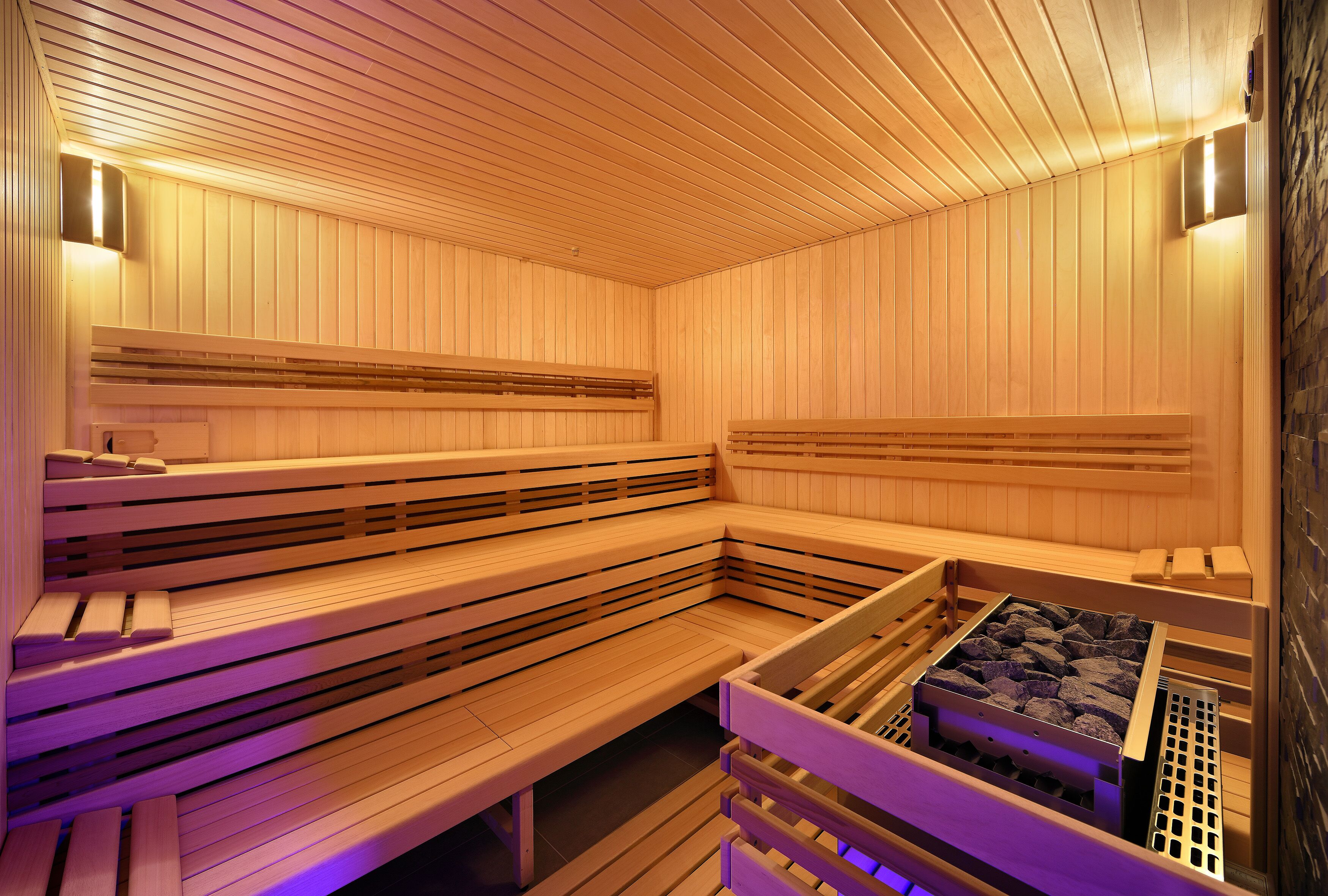 Eine Sauna mit Holzbänken und einer Steinwand.
