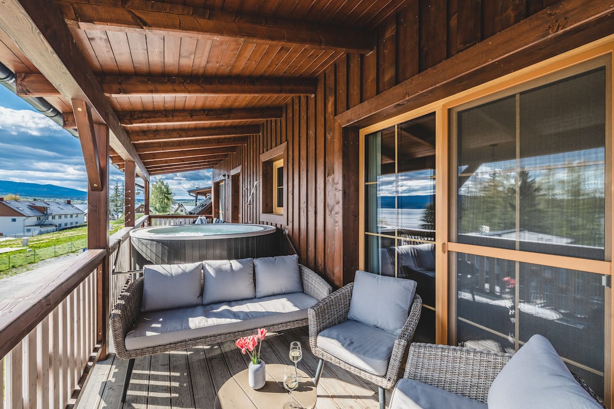 Eine Holzterrasse mit Korbmöbeln, einem Whirlpool und Blick auf die Landschaft.