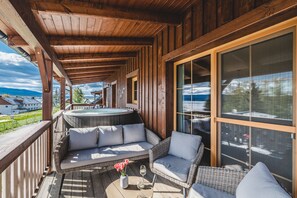 A wooden deck with wicker furniture, a hot tub, and a view of the landscape. - Hotel Resort Relax (Cerna V Posumavi)