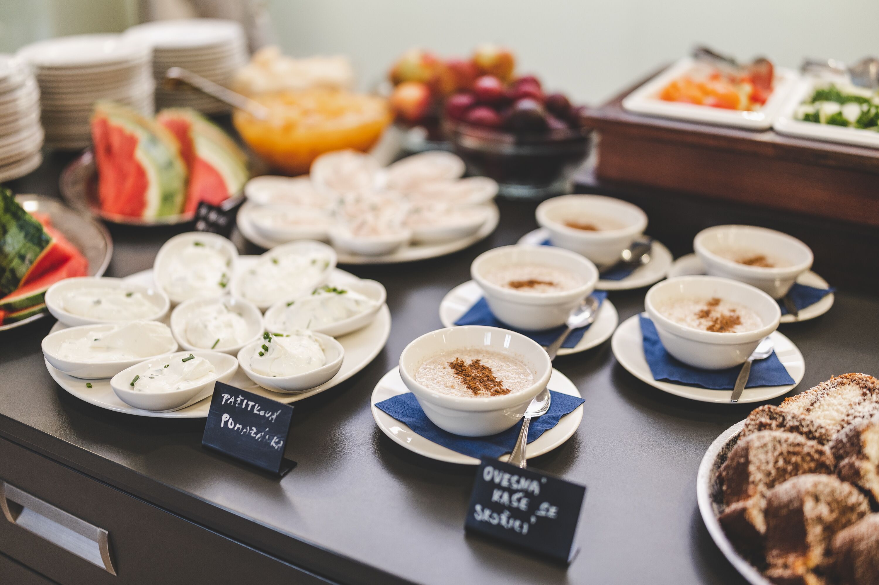 Un bufé con diversos platos, incluyendo yogur, avena y productos de pastelería.