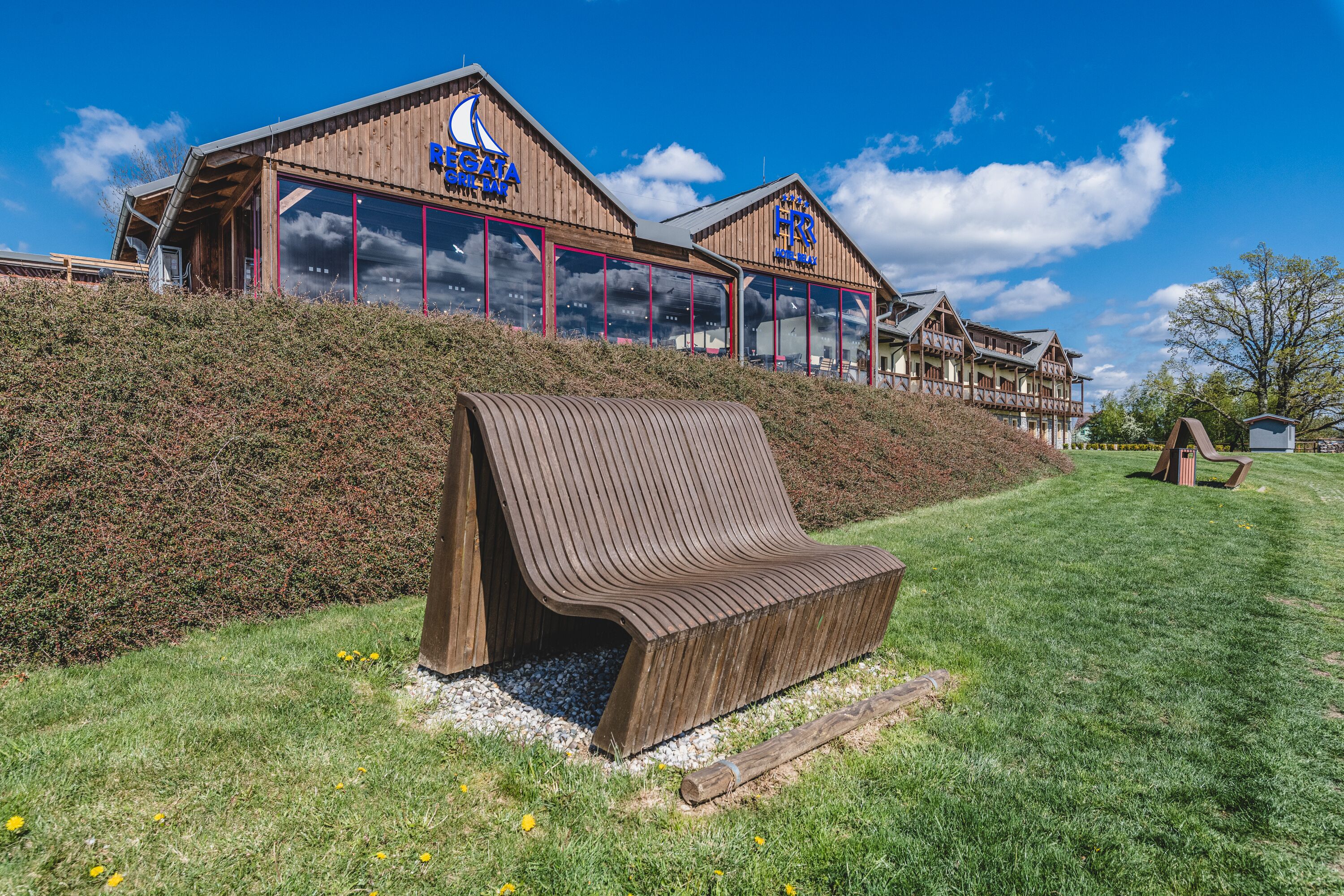 A wooden building with large windows and a bench in front.