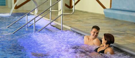 A couple in a hot tub with a metal ladder and wooden steps.