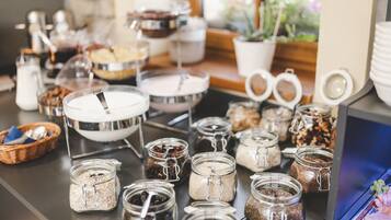 A buffet setup with various food items in jars and bowls, a milk jug, and a basket with utensils.