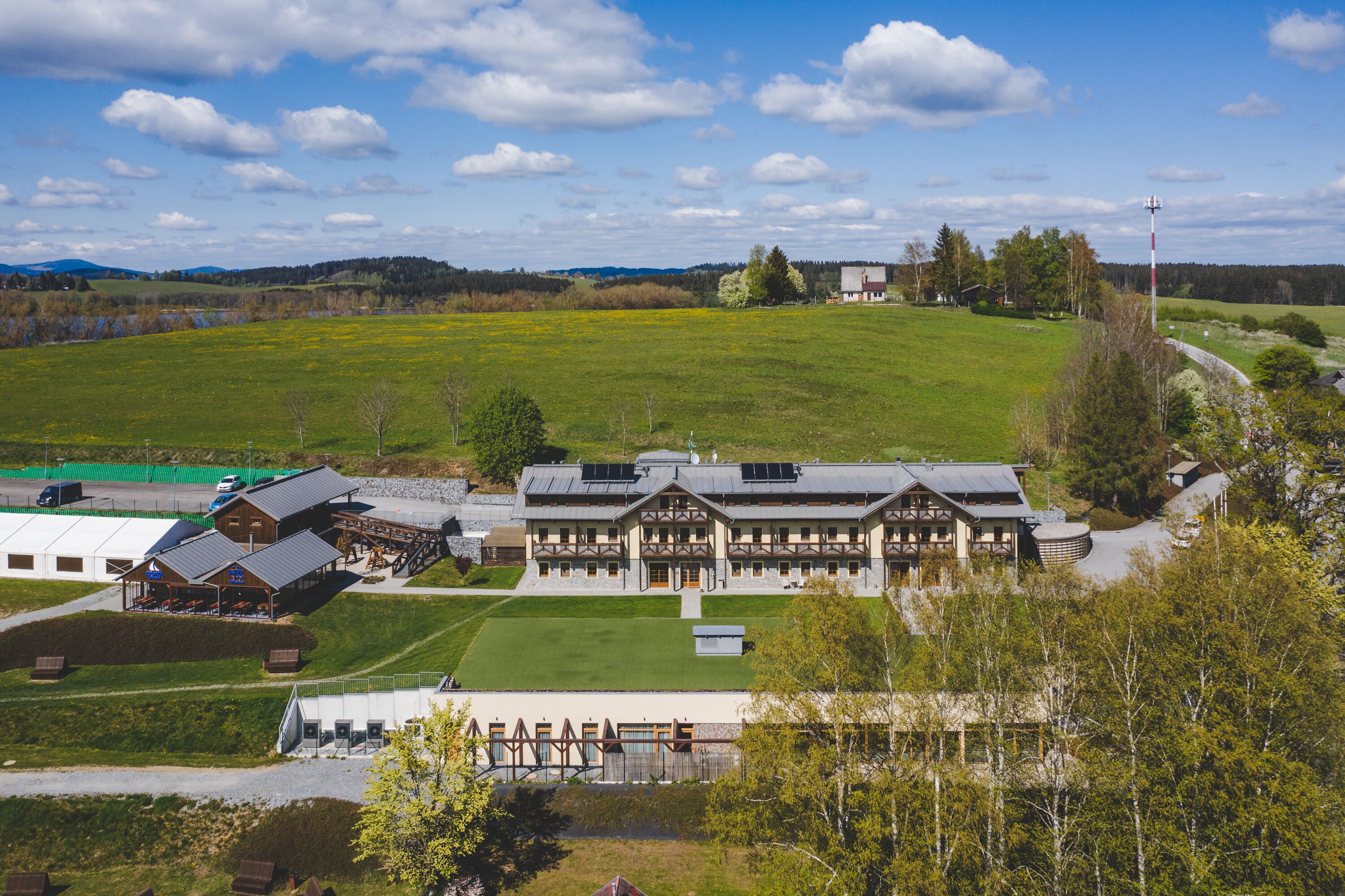 A large lodge with multiple guest rooms, a central dining area, and a well-maintained lawn.