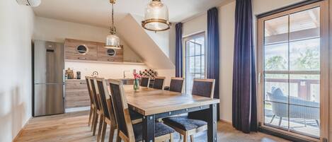 Una cocina moderna con refrigerador empotrado, armarios de madera y un comedor con mesa y sillas de madera.