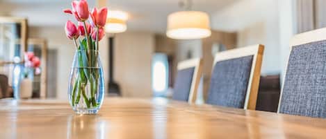 Una mesa de comedor con un florero de vidrio transparente que contiene tulipanes rosados.