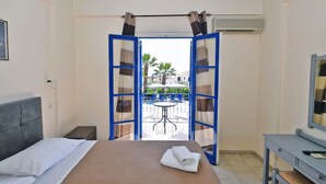 Habitación de hotel con cama, escritorio y vistas a un espacio exterior con mesa y sillas.