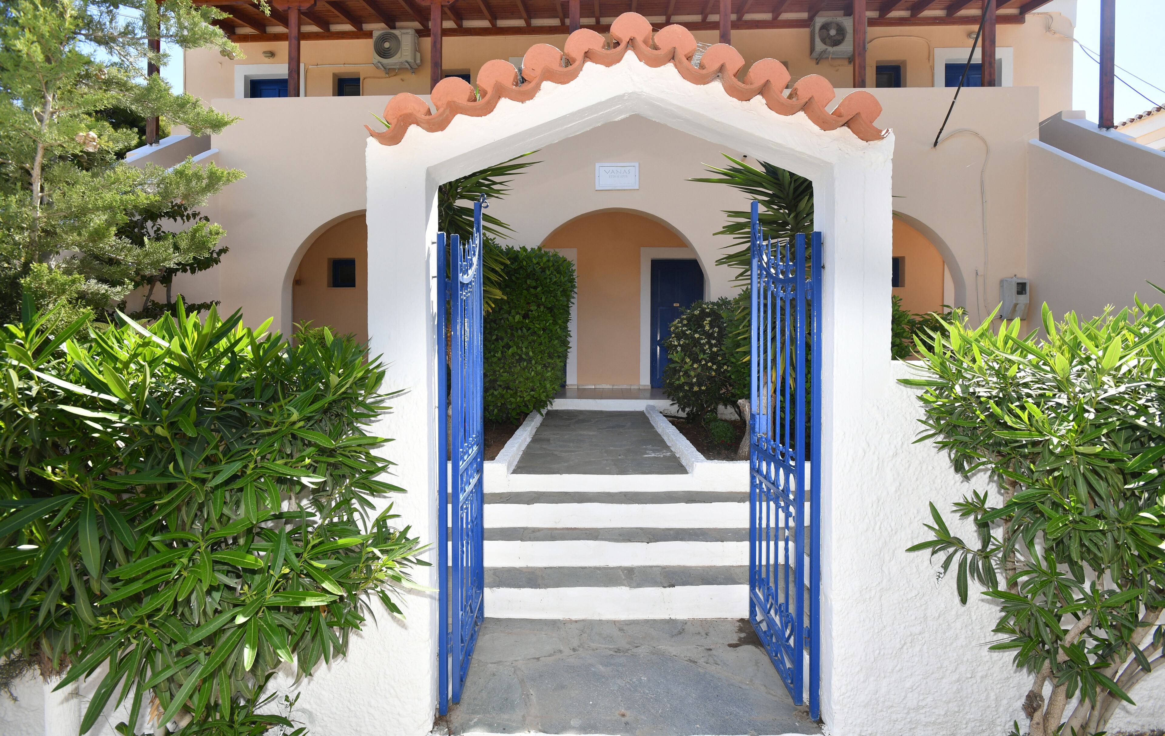 A white building with a blue gate and steps leading to an entrance.
