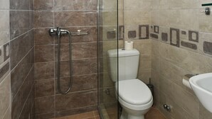 Un baño con ducha de vidrio, inodoro y lavamanos.