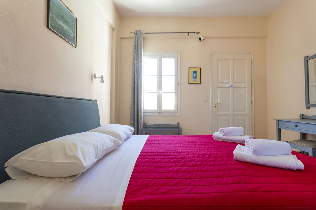 A hotel room with a bed, a desk, a chair, and a window with curtains.