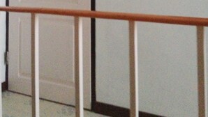 A white door with a small blue sign above it, a white wall, and a metal handrail in the foreground. - Onn Inn at Cha-am (Cha-am)