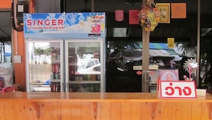 A Singer store with a refrigerated display case, a cash register, and two red cushioned chairs in front. - Onn Inn at Cha-am (Cha-am)