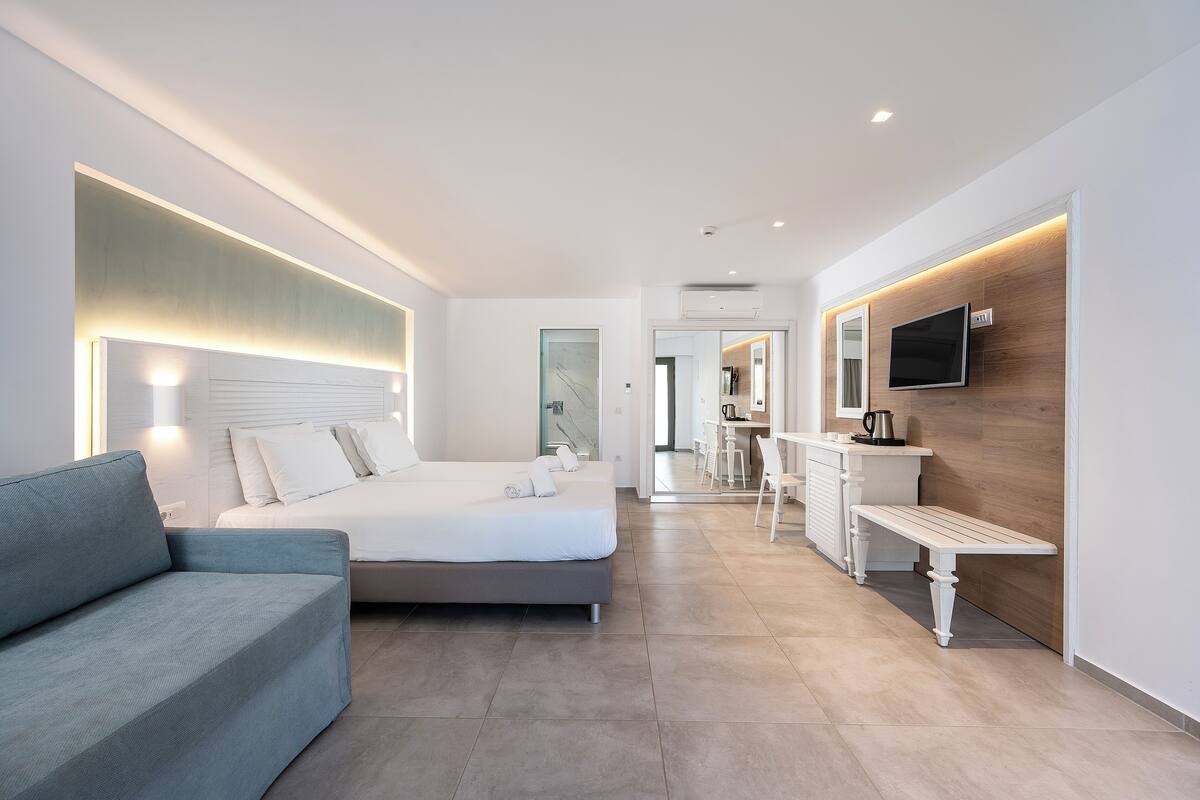 Una habitación de hotel moderna con cama, sofá, escritorio y televisor.