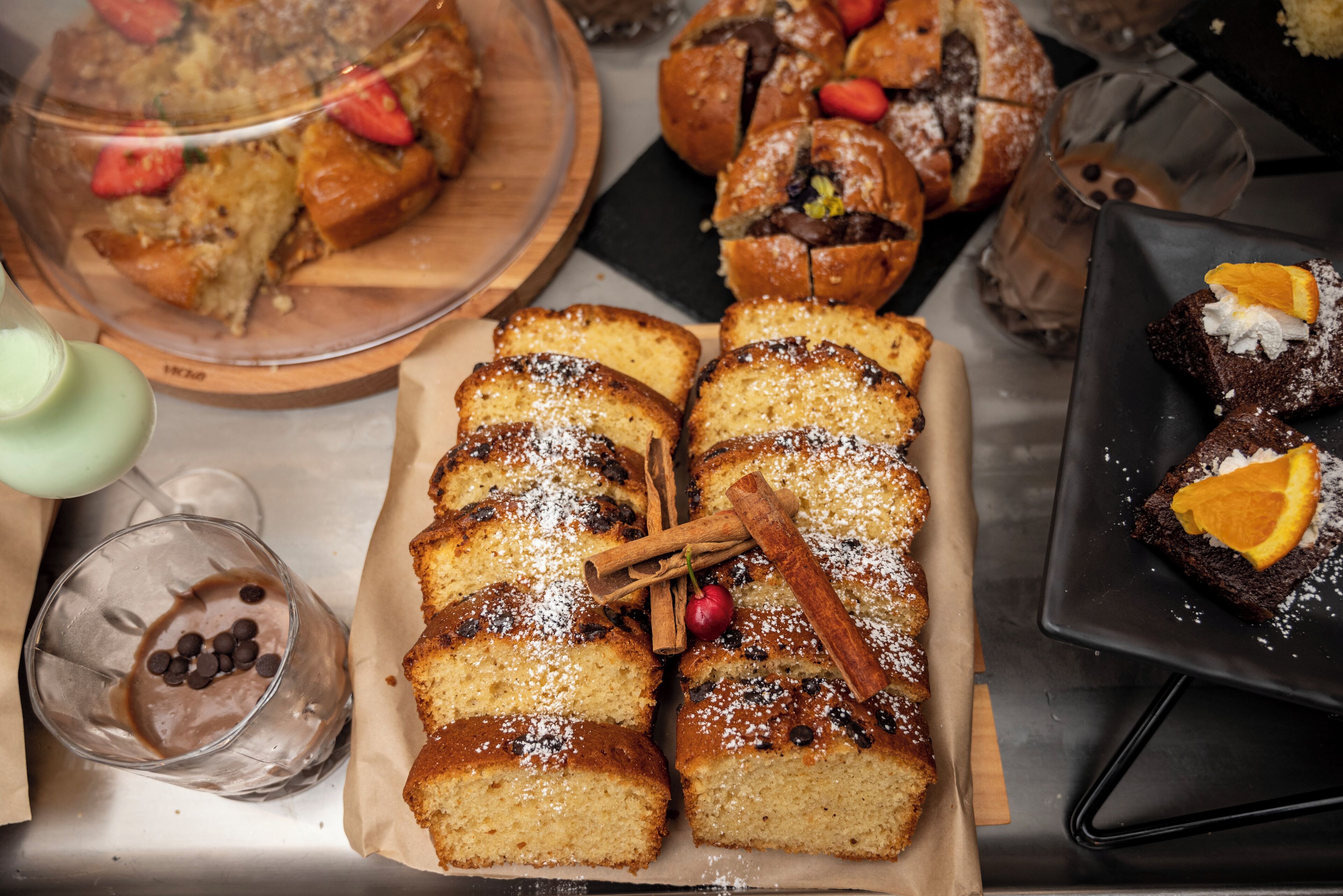 Variedad de productos de panadería, como pan y pasteles, sobre una mesa.