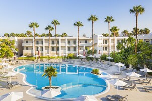 Una piscina al aire libre, sombrillas, sillones reclinables de piscina