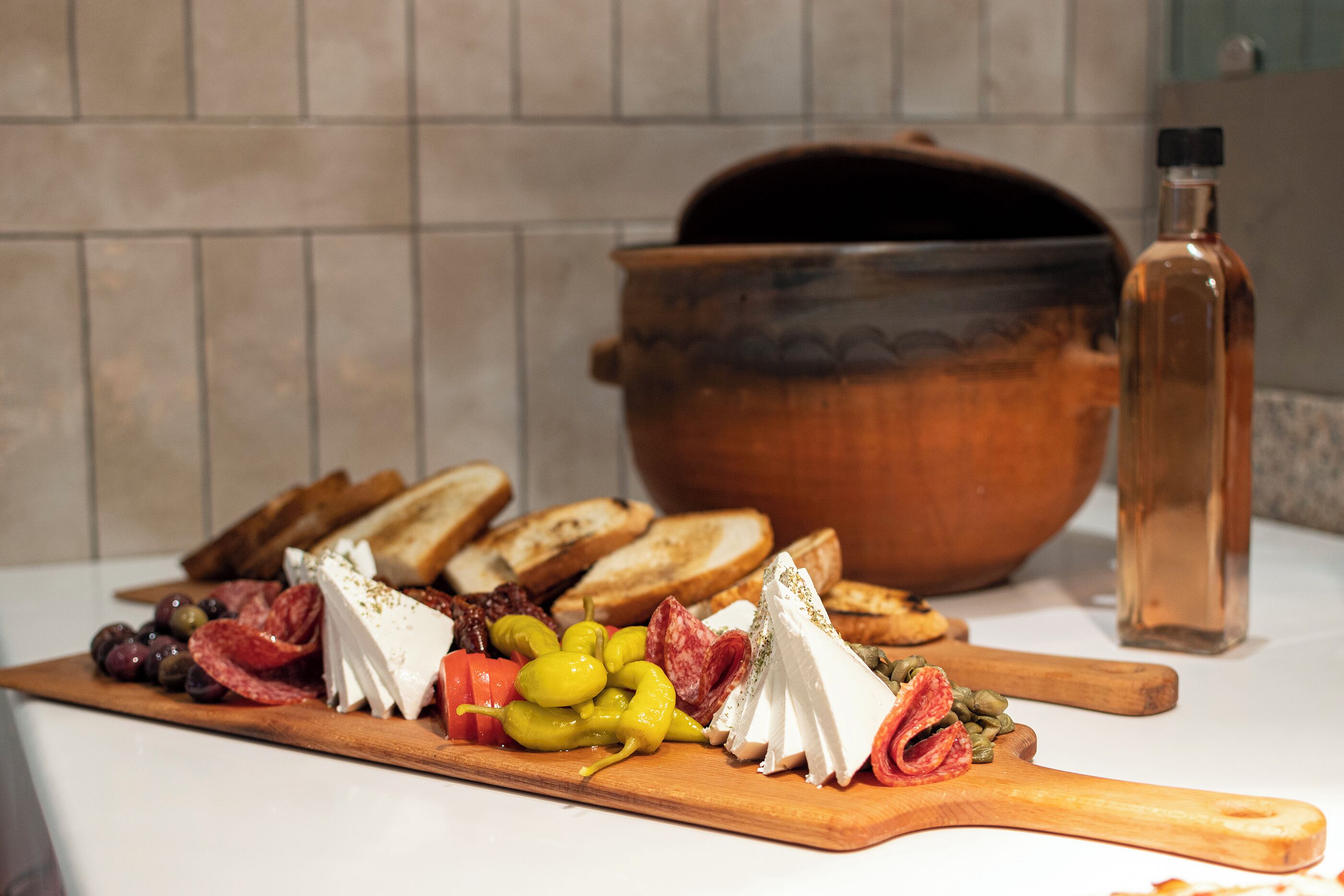 A charcuterie board with various cheeses, meats, and olives on a wooden board.