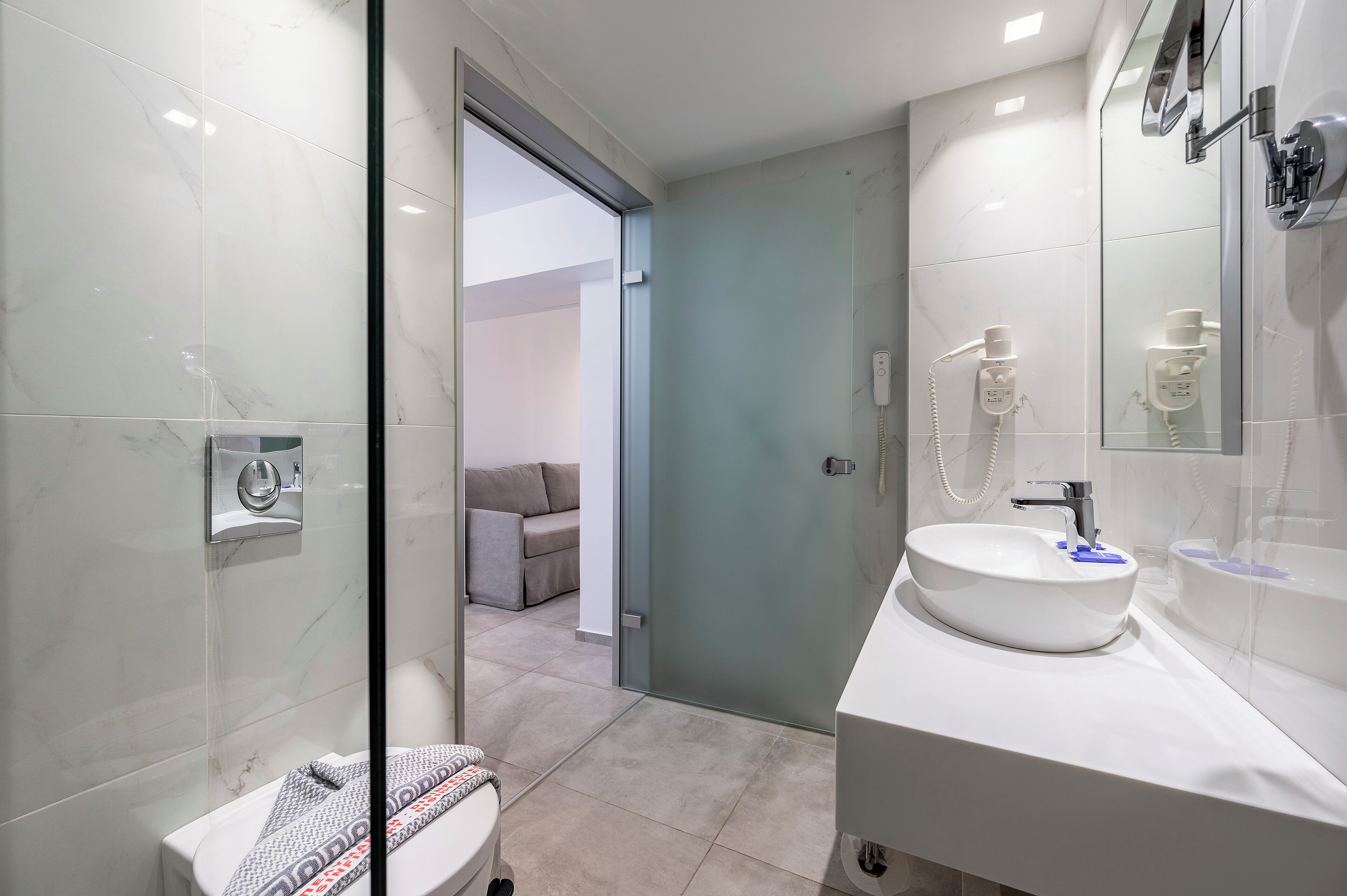 A modern bathroom with a glass shower enclosure, a white sink, and a toilet.