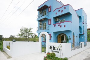 A multi-story building with a blue facade, balconies, and a white entrance gate. - Ola B&B - Peng's family (Taitung)