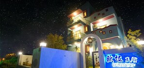 A multi-story hotel with a modern architectural design, featuring balconies and a well-lit entrance. - Ola B&B - Peng's family (Taitung)