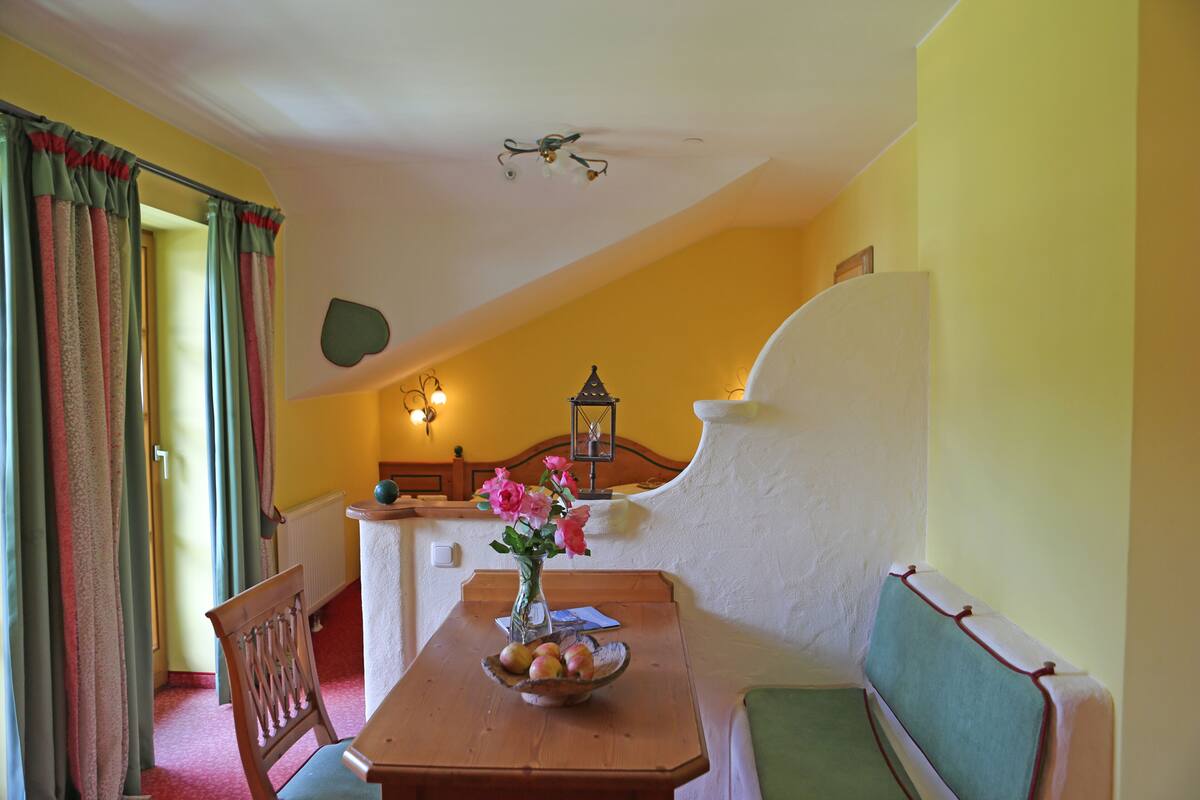 A dining area with a wooden table, a bowl of fruit, and a vase of flowers.