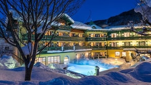 A multi-story hotel with balconies and a pool area, surrounded by snow. - Hotel Sommerhof (Gosau)