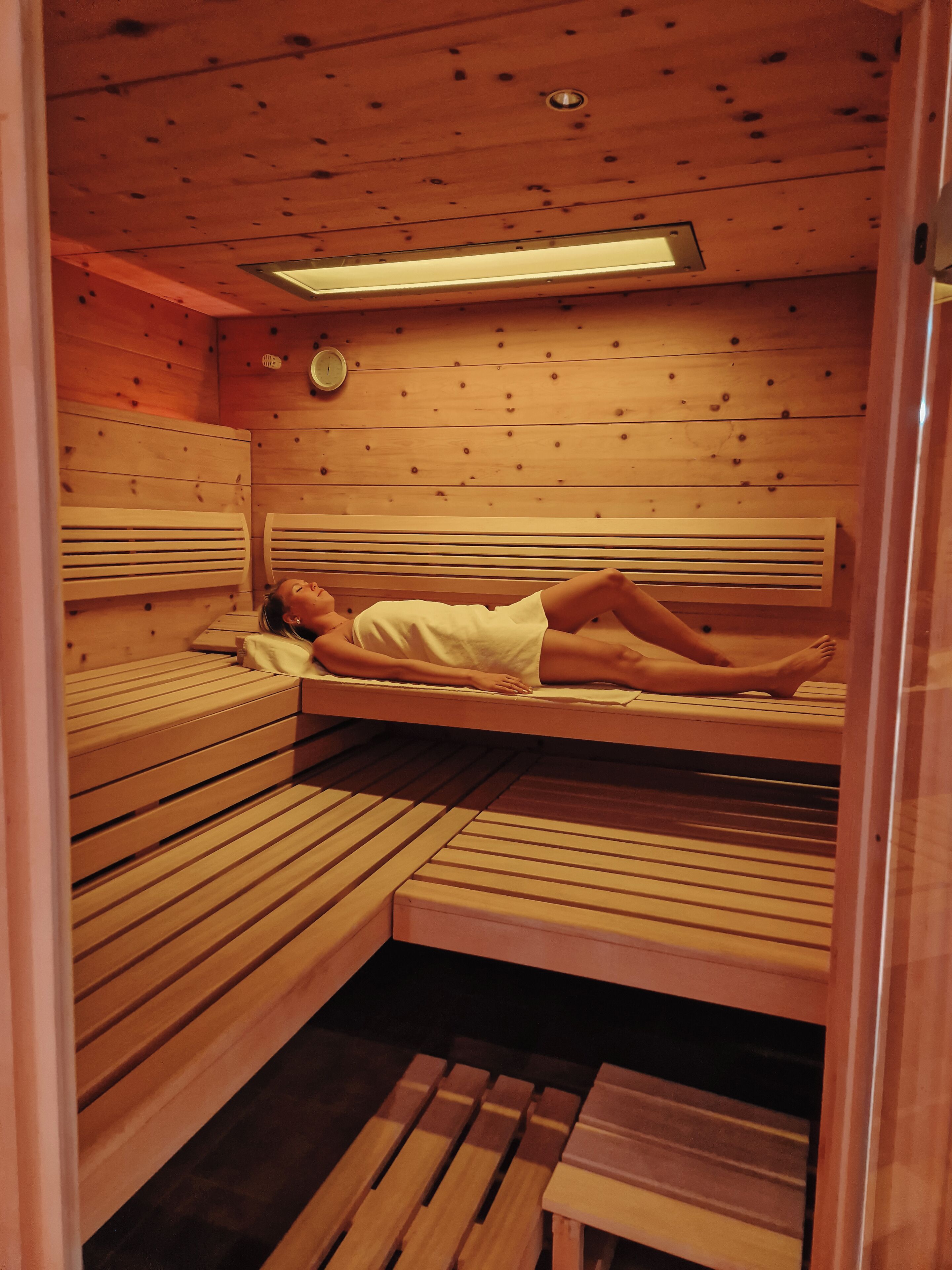 Una sala de sauna con bancos de madera y una persona acostada en un banco.