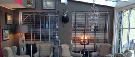 Un salon avec des fauteuils à motifs, une table basse en verre et un lustre.