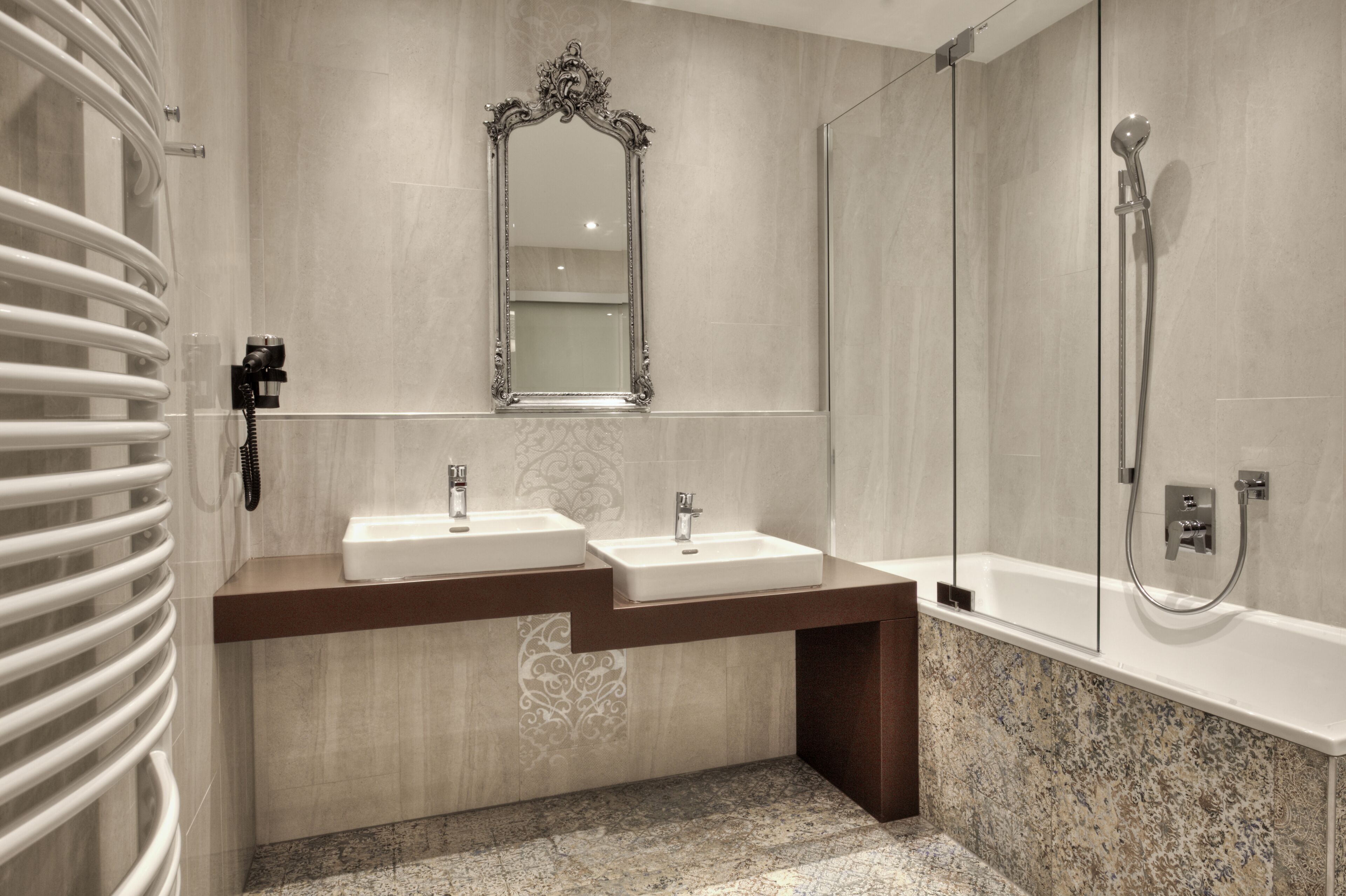 A modern bathroom with two sinks, a large mirror, a shower, and a built-in heater.