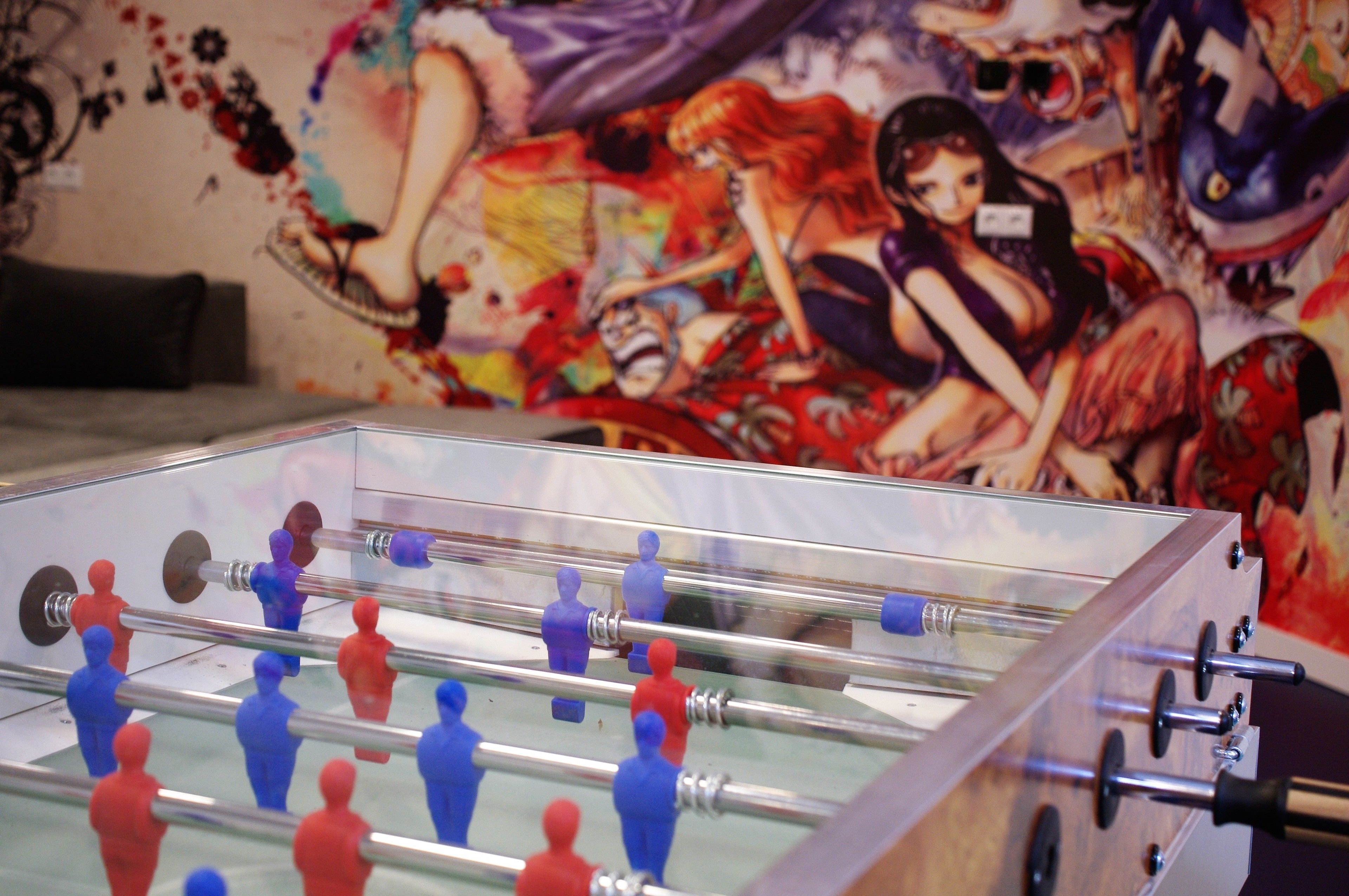 A foosball table in a room with a colorful mural on the wall.