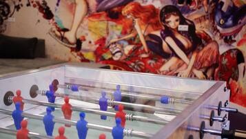 A foosball table in a room with a colorful mural on the wall.